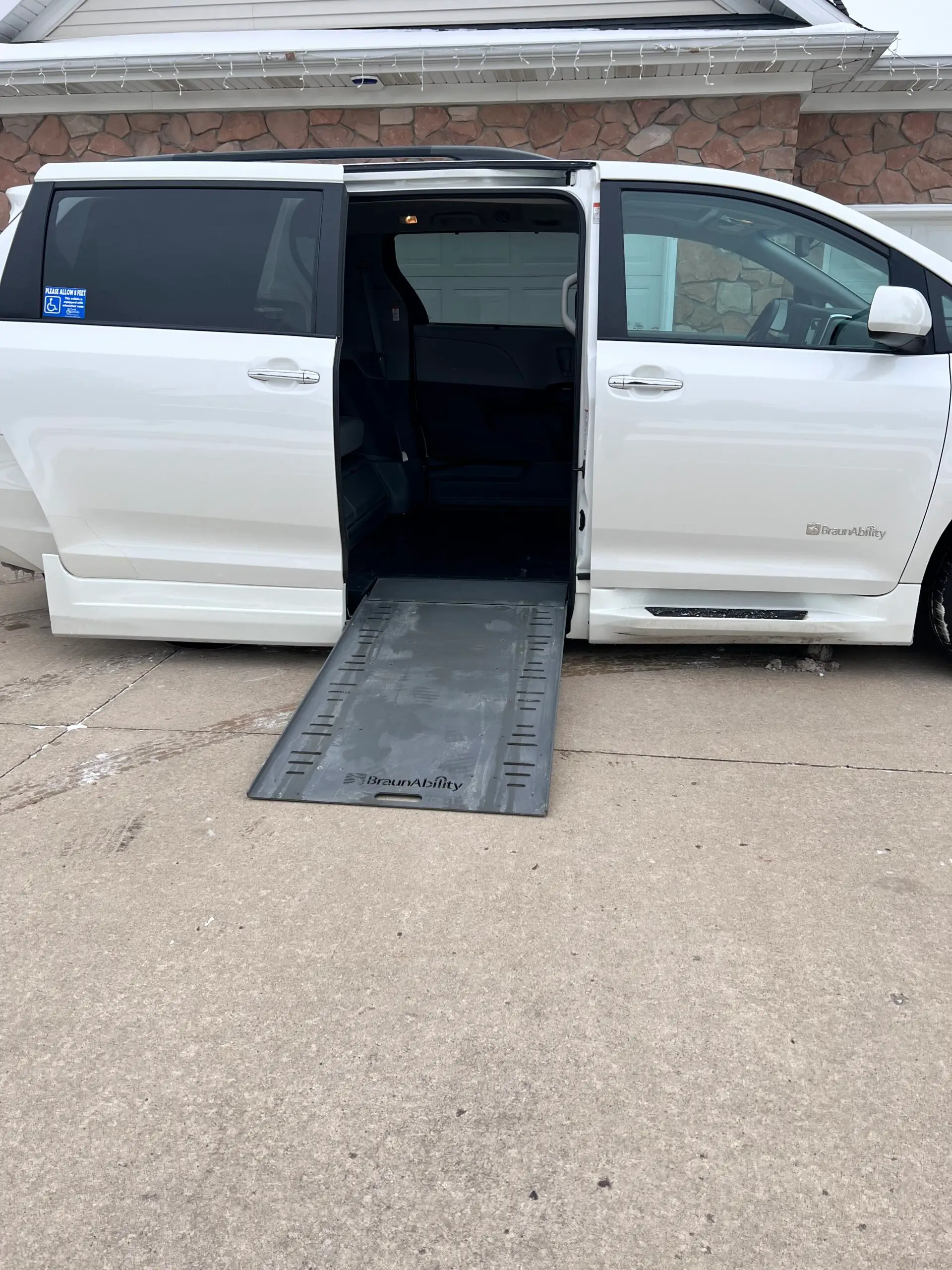 A white van with the door open and ramp in it.